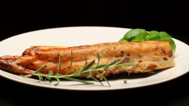 Geräucherter Karpfen mit aromatischen Kräutern auf weißem Teller, rotierend — Stockvideo