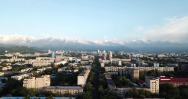 Dağların üzerinde bulutlar ve gün batımında Almaty şehri.