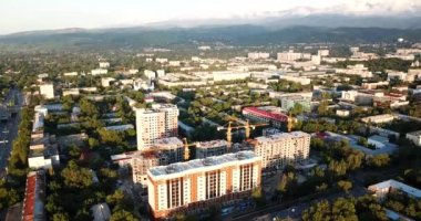 Dağların üzerinde bulutlar ve gün batımında Almaty şehri.