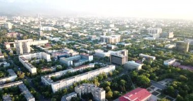 Dağların üzerinde bulutlar ve gün batımında Almaty şehri.
