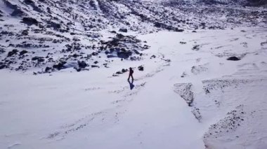 Bir dağcı karlı dağların arasında yürüyor..