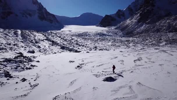 En klatrer går blant snødekte fjell. – stockvideo