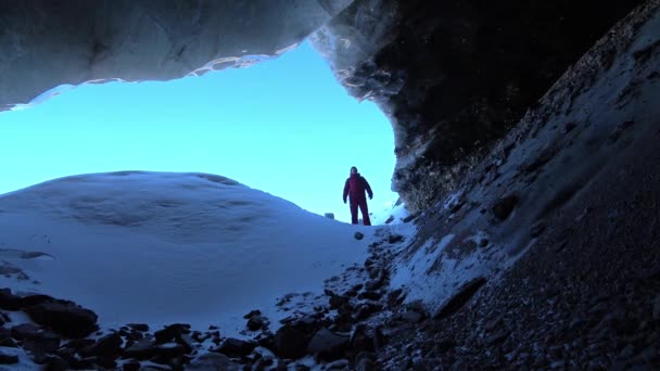 The guy explores the ice cave. A dangerous place. — Stock Video