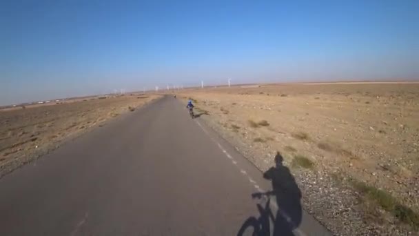 Cyklister rider längs vägen med utsikt över väderkvarnar. — Stockvideo