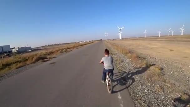 Ciclistas passeio ao longo da estrada com vista para moinhos de vento. — Vídeo de Stock