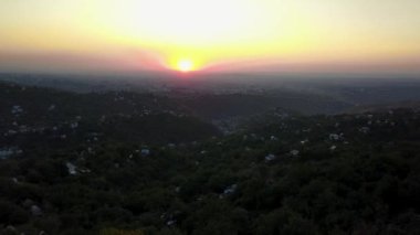 Almaty 'nin yeşil tepeleri arasında kırmızı gün batımı.