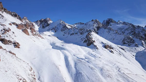 Snow mountain peaks with rocks. View from a drone.