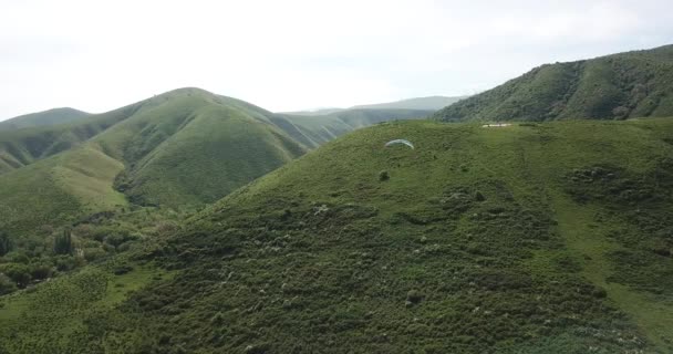 Paragliding v horách. Zelená pole, kopce. — Stock video