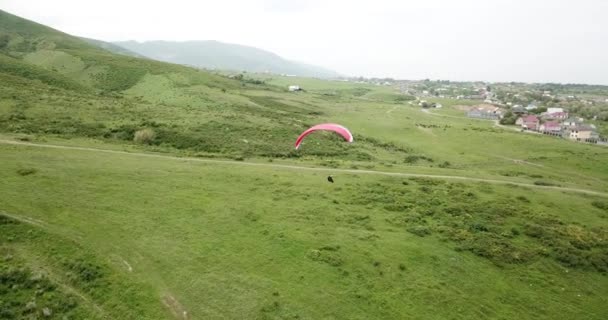 Paragliden in de bergen. Groene velden, heuvels. — Stockvideo