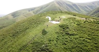 Dağlarda paraşütle atlamak. Yeşil tarlalar, tepeler.