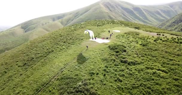 Paragliding v horách. Zelená pole, kopce. — Stock video