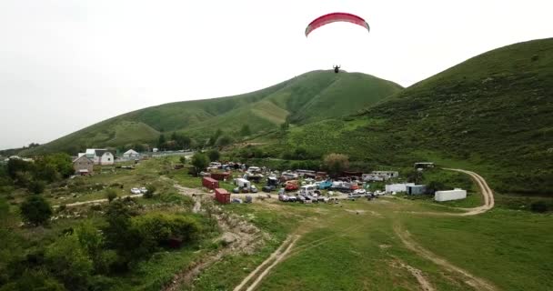 Dağlarda paraşütle atlamak. Yeşil tarlalar, tepeler. — Stok video