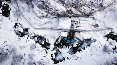 Karlı ormanda ve dağlarda sıcak pınarlar. Nehrin yanındaki beyaz geçitten drone 'un üst görüntüsü. Radon suyu fıçıları var. Buhar var, insanlar banyo yapıyor. Almarasan, Almaty.