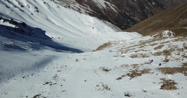 Los turistas caminan a lo largo de un sendero de nieve en las montañas. — Vídeos de Stock