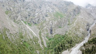 Kayaların arasında yüksek bir şelale. Bir İHA görüntüsü.