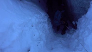 A climber descends into an ice cave.