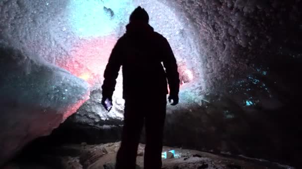 Un tipo en una cueva de hielo con una luz de linterna. — Vídeos de Stock