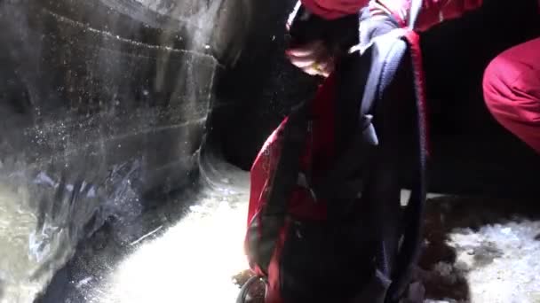 El tipo en la cueva de hielo abre una mochila roja. — Vídeo de stock