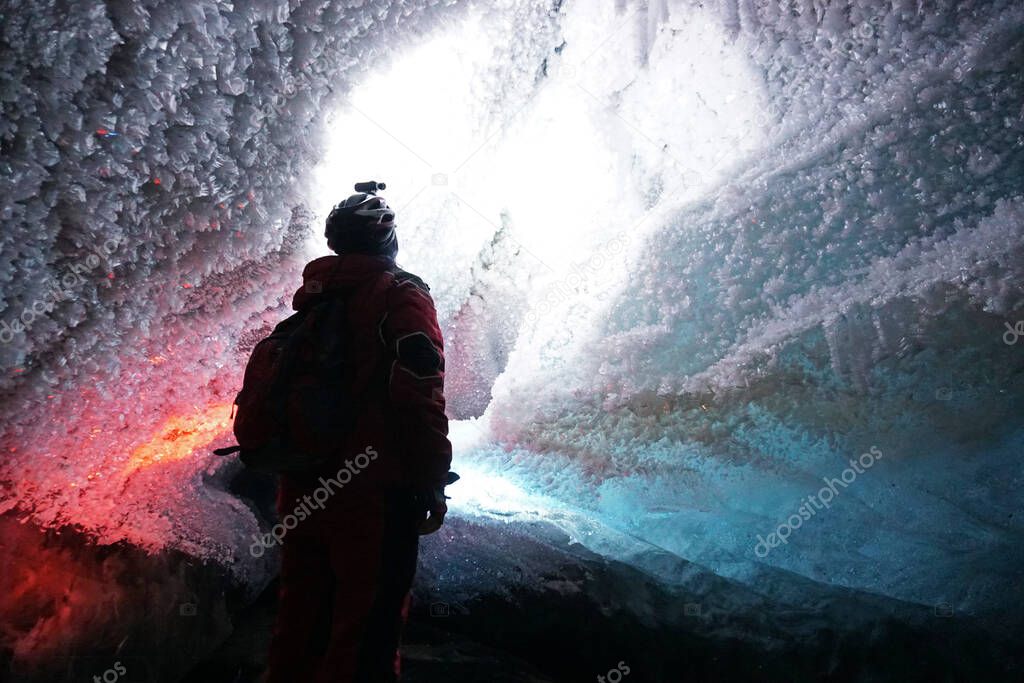 A guy in an ice cave with a lantern light.