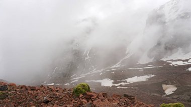Beyaz bulutlar ve karlı zirveler. Bir sürü büyük taş.
