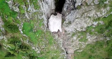 Dik dağ kayalıkları ve bir buz mağarası manzarası..