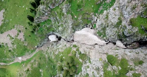 Bovenaanzicht op steile bergkliffen en een ijsgrot. — Stockvideo