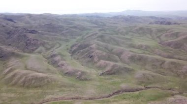 Yeşil tepeler ve taşlı geçitler görünüyor..