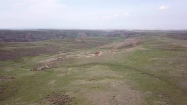 Yeşil tepeler ve taşlı geçitler görünüyor..