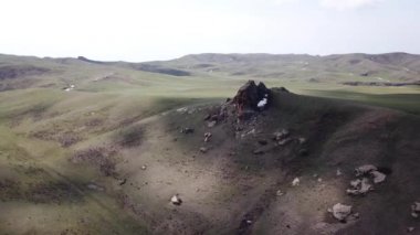 Yeşil bir tepenin kenarında kocaman bir kaya..