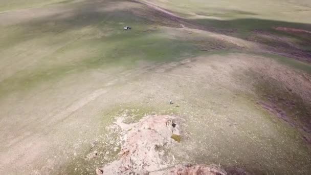 Uma rocha enorme na borda de uma colina verde. — Vídeo de Stock