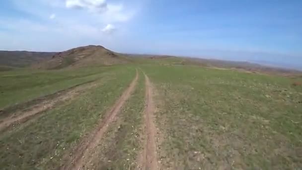 Rowerzysta jeździ po drodze na zielonym polu. — Wideo stockowe