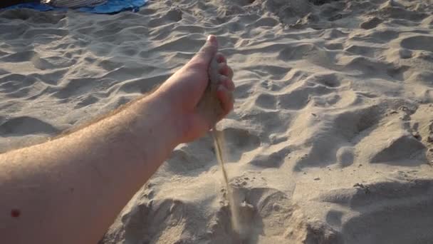 Arena cae de una mano de hombre en la playa. — Vídeo de stock