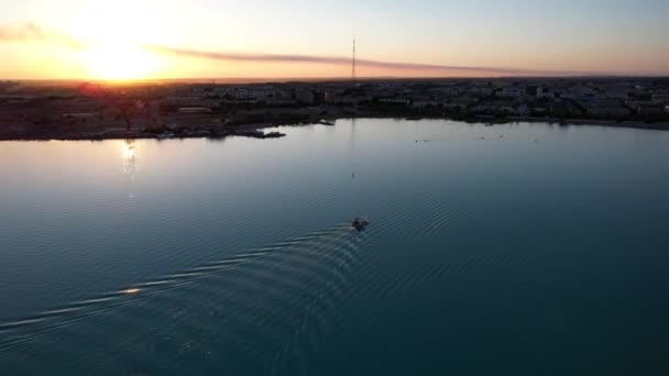 Le bateau navigue dans la baie au coucher du soleil près de la ville — Video