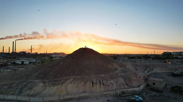 Deux silhouettes sur la montagne. Usine fume. — Photo