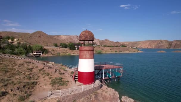 Weißer und roter Leuchtturm am Ufer des Sees — Stockvideo