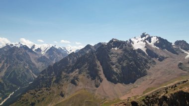 Bazı yerlerde karla kaplı yüksek dağlar. Yeşil çimenler büyür. Büyük kayalar ve kayalıklar. Uzakta Talgar ve Nursultan tepelerini görebilirsiniz. Kayalık bir vadi. Yüksekten kürek çekmek. Kazakistan