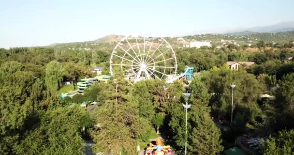 Un parc urbain avec des manèges et une grande roue. — Video
