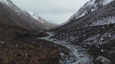 Hava manzarası engebeli dağlık bir vadiden akan sarmal bir nehri yakalar kayalık arazi ve akan suyun karşıtlığını gözler önüne serer.