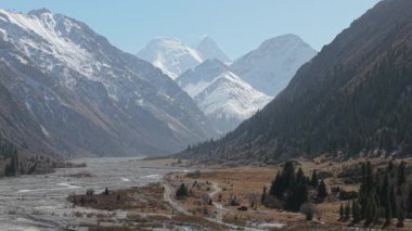 Karla kaplı tepeleri ve kıvrımlı bir nehri gözler önüne seren görkemli dağ manzarası, kamera, arazinin doğal güzelliğini ve dokusunu gözler önüne seriyor.