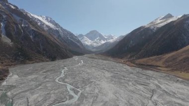 Hava perspektifi kayalık bir vadiden akan çarpıcı dağları ve kıvrımlı nehri yakalar, doğal güzelliği ve uçsuz bucaksızlığı gözler önüne serer, kamera ileri doğru hareket eder.