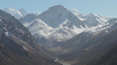 Karla kaplı tepeler ve derin vadilerin yer aldığı görkemli dağ manzarası, kameranın, sahnenin karmaşık detaylarını ortaya çıkarmak için yavaşça yaklaşmasıyla, arazinin doğal güzelliğini gözler önüne seriyor.