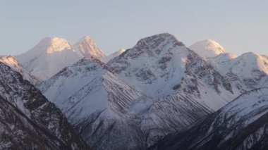 Karla kaplı görkemli dağlar, engebeli araziyi ve dokuları gösteren dinamik bir dizi halinde çekiliyor. Kamera çarpıcı tepe ve vadilere yaklaştıkça, karmaşık ayrıntılar ortaya çıkıyor.
