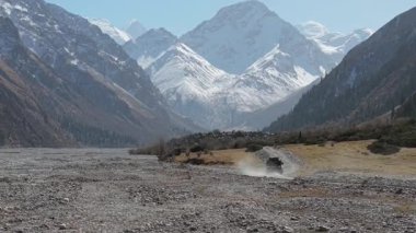 Aracın arka planında dağlar olan kayalık arazide hareket etmesi engebeli araziyi ve doğal güzelliği gözler önüne seriyor. Kamera, dinamik sahneyi yakalamak için hareketi takip ediyor.