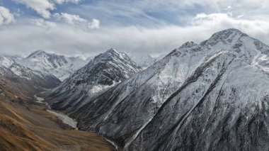 Uçsuz bucaksız karlı dağların geniş manzarası engebeli araziler, vadiler ve aşağıdaki kıvrımlı bir nehir doğanın güzelliğini ve dağlık manzaranın ihtişamını gözler önüne seriyor.