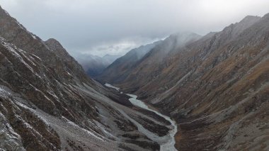 Engebeli tepeler ve dramatik bulut örtüleriyle çevrili dolambaçlı bir nehrin bulunduğu bir dağ vadisinin nefes kesici manzarası doğanın güzelliğini ve manzaranın sükunetini gözler önüne seriyor.