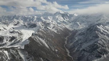 Hava perspektifi, karla kaplı muhteşem tepeleri ve aşağıdaki kıvrımlı nehri yakalar. Uçsuz bucaksız manzarayı gözler önüne serer. Gökyüzünde sürüklenen bulutlarla, kamera sorunsuzca hareket eder.