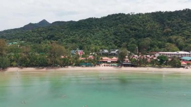 Phuket, Tayland 'daki karon plaj beldesinin çarpıcı hava manzarası, turkuaz suları, beyaz kum, yüzme havuzları, bungalovlar ve yemyeşil bitki örtüsünü gösteriyor.