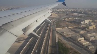 Yoğun bir şehir otoyolu ve binalar üzerinde yer alan uçak kanadı, yolun ve çevreleyen yapıların net bir şekilde görülme mesafesini gözler önüne seriyor.