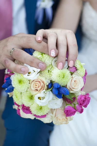 手中的结婚戒指和美丽的婚礼花束 — 图库照片