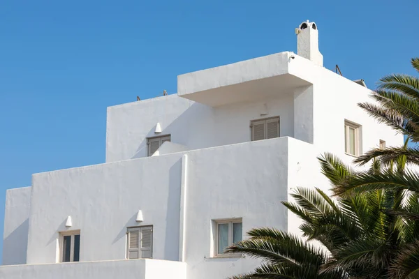 White villa, typical Greek architecture on the edge of the caldera. Palm trees. Fira, Santorini Island, Greece.